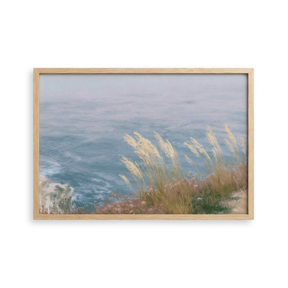 A framed painting depicting a serene coastal landscape with a rocky cliff overlooking the ocean.