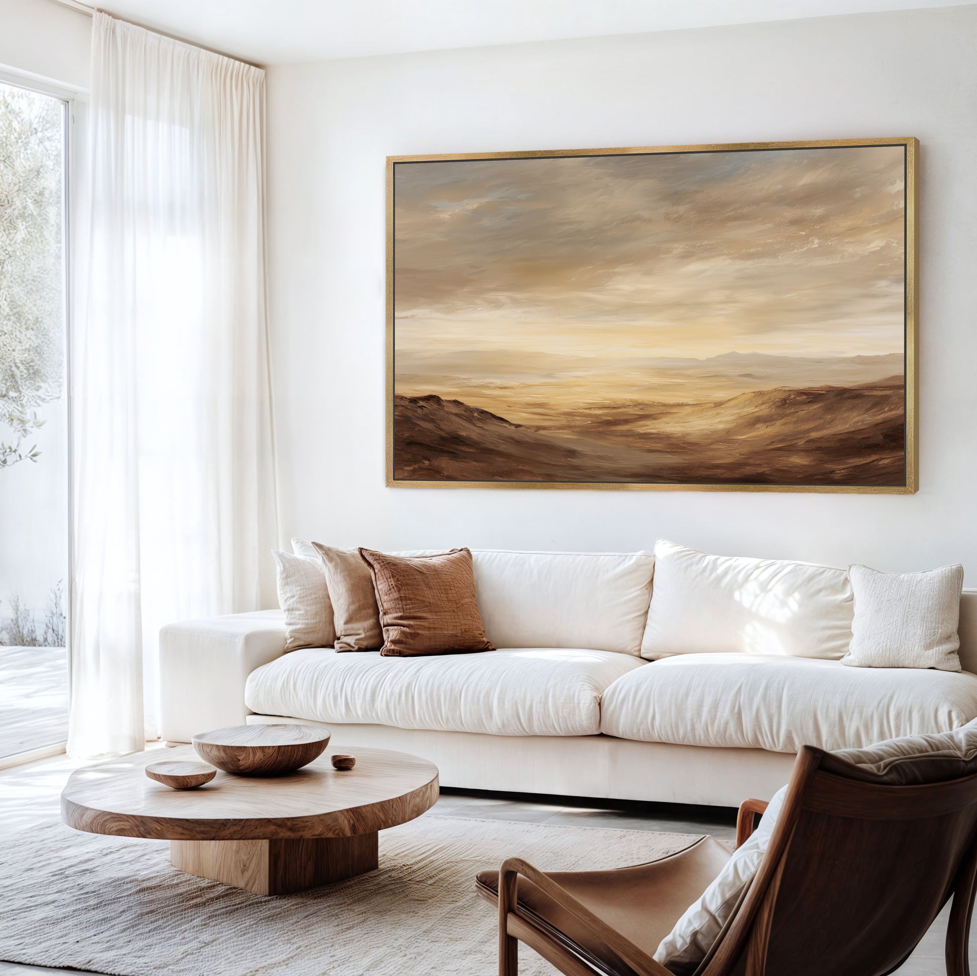 a modern living room with a large landscape painting hanging on the wall above a white sofa. The room is furnished with a wooden coffee table, a brown leather armchair, and a wooden side table. The overall color scheme of the room is neutral, with the brown leather armchair and wooden coffee table adding a touch of warmth to the space.