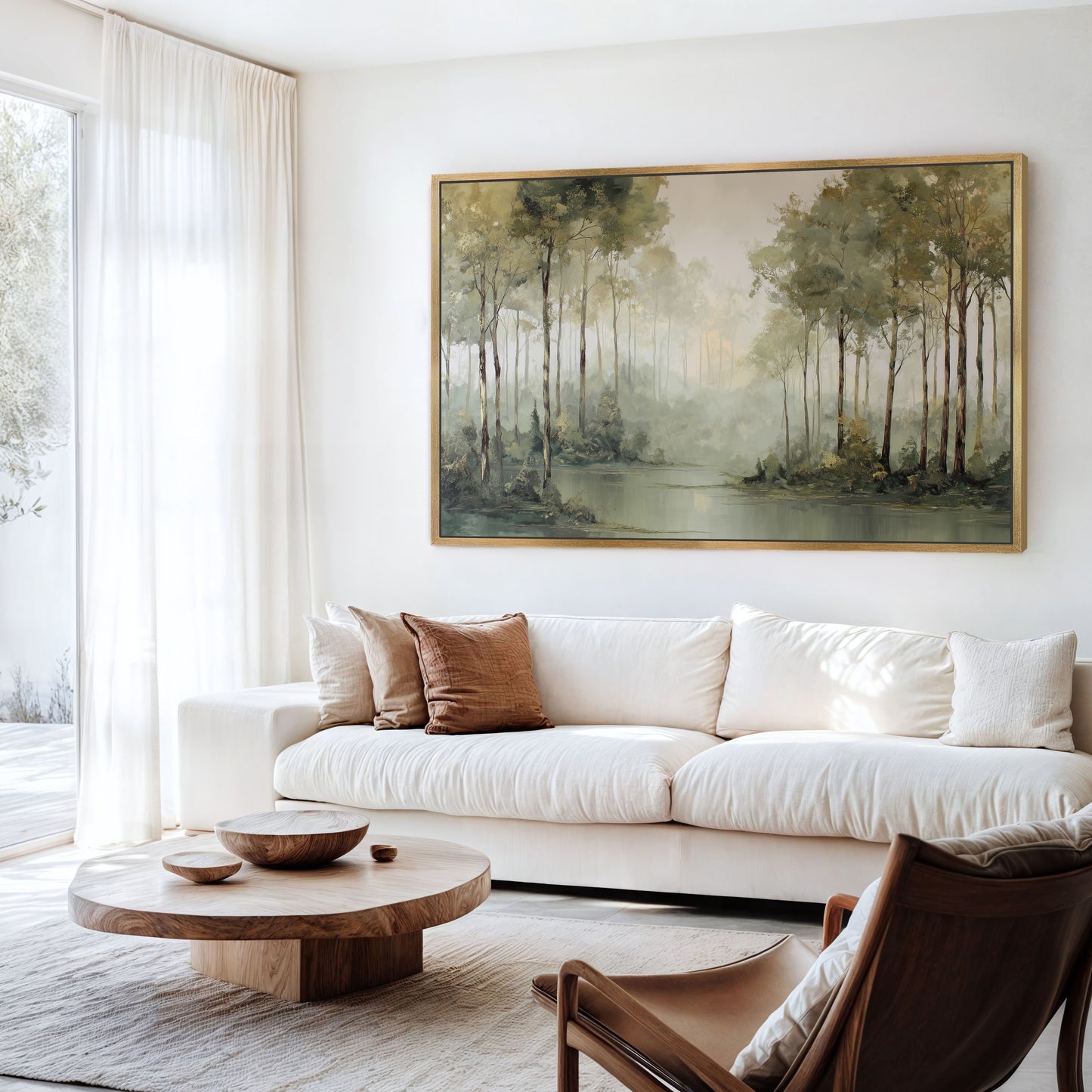 Misty forest edge wall art with a gold frame styled in a bright modern living room.