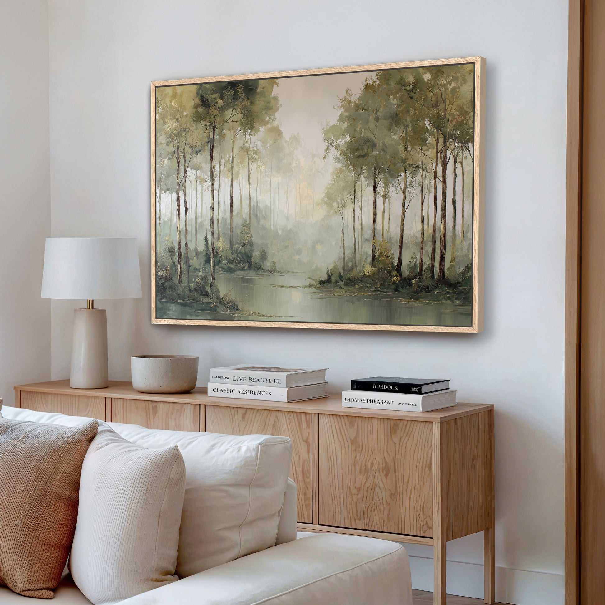 Misty forest edge wall art in a natural wood frame displayed above a neutral modern living room console.