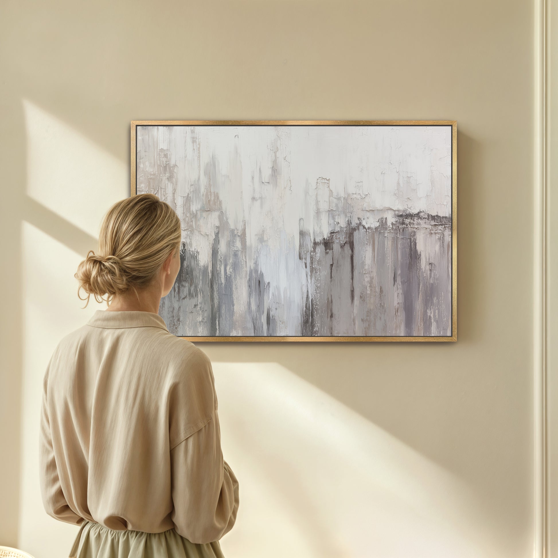 Woman viewing neutral abstract wall art on beige wall