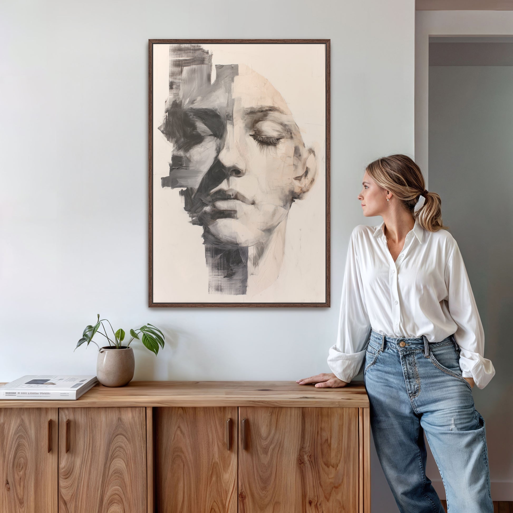 Abstract portrait wall art in walnut brown frame, styled in a modern living space with mid-century wood console and indoor plant.