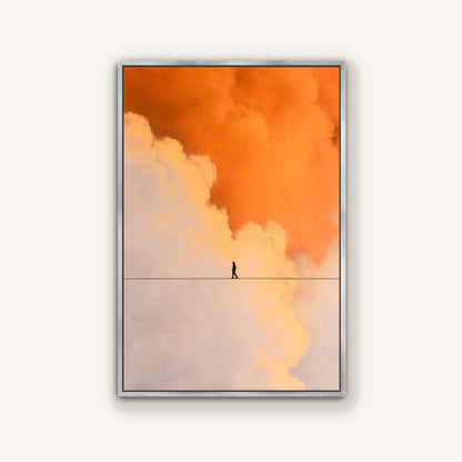 Modern wall art of a figure crossing a line in glowing orange and white clouds, displayed in a sleek silver frame.