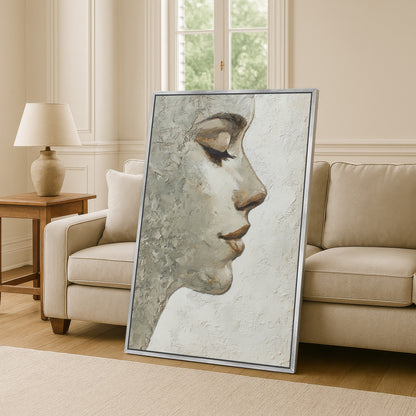 Minimalist portrait canvas with silver frame leaning against sofa in classic neutral living room.