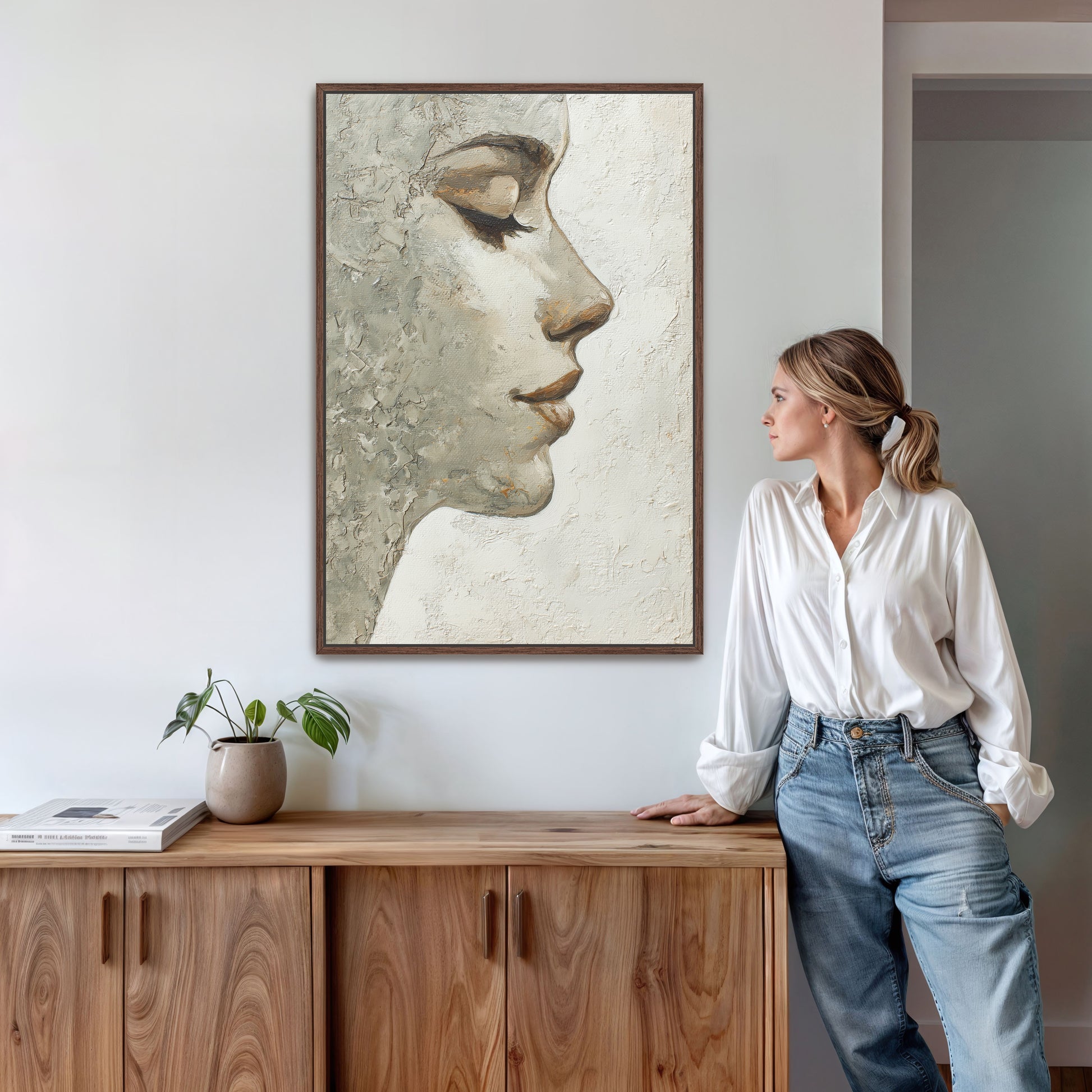 Abstract portrait wall art with walnut frame in bright modern interior next to woman in white blouse.